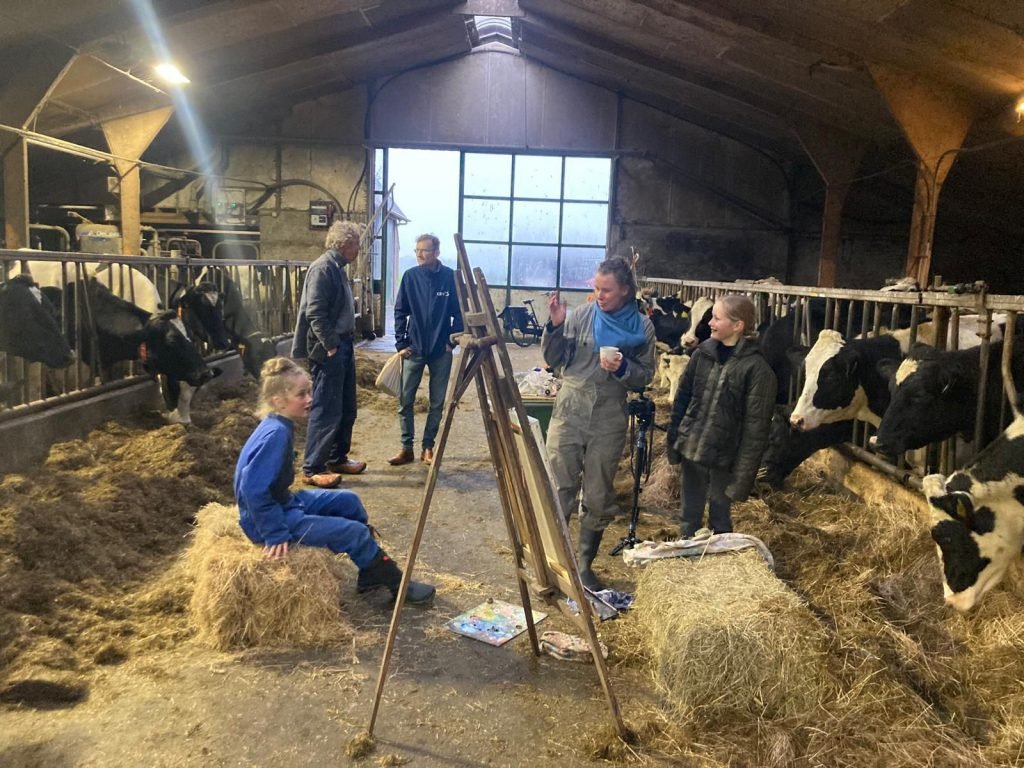 Opnames voor Portret van een Dochter: de schildersezel tussen de koeien in de stal, buren kijken toe
